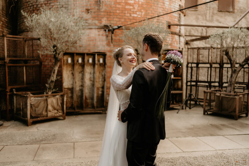 Hochzeitsfotograf fängt liebevollen Moment zwischen Braut und Bräutigam vor industrieller Kulisse ein