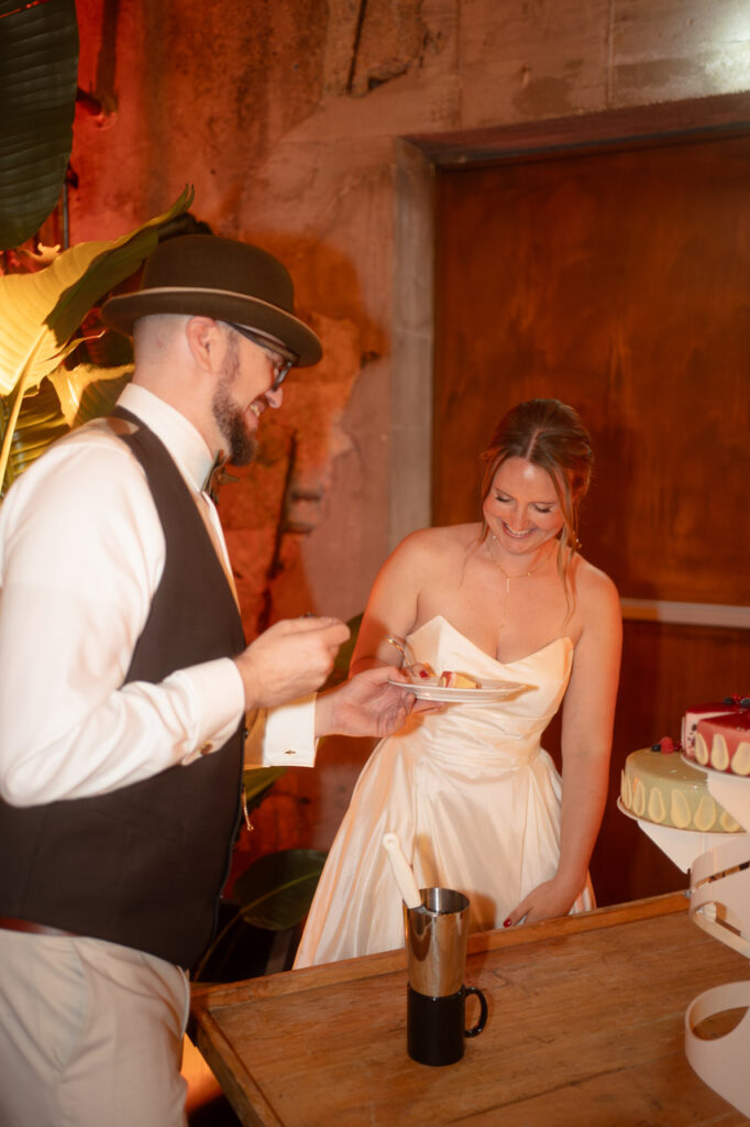 Ein emotionaler Moment, festgehalten vom Hochzeitsfotograf: Das Brautpaar lacht gemeinsam beim Anschneiden der Hochzeitstorte