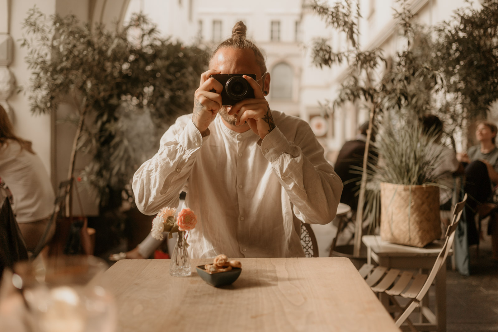 Christian Messner hält im Café seine Kamera hoch und fotografiert – authentischer Moment eines leidenschaftlichen Fotografen