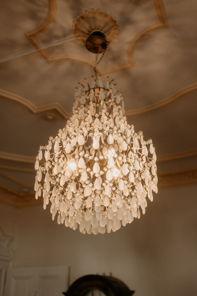 Nahaufnahme eines prunkvollen Kronleuchters mit weichem Lichtspiel an der Decke