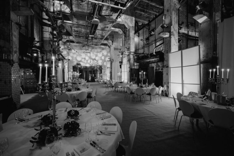 Innenaufnahme einer Hochzeit mit gedeckten Tischen und industrieller Architektur