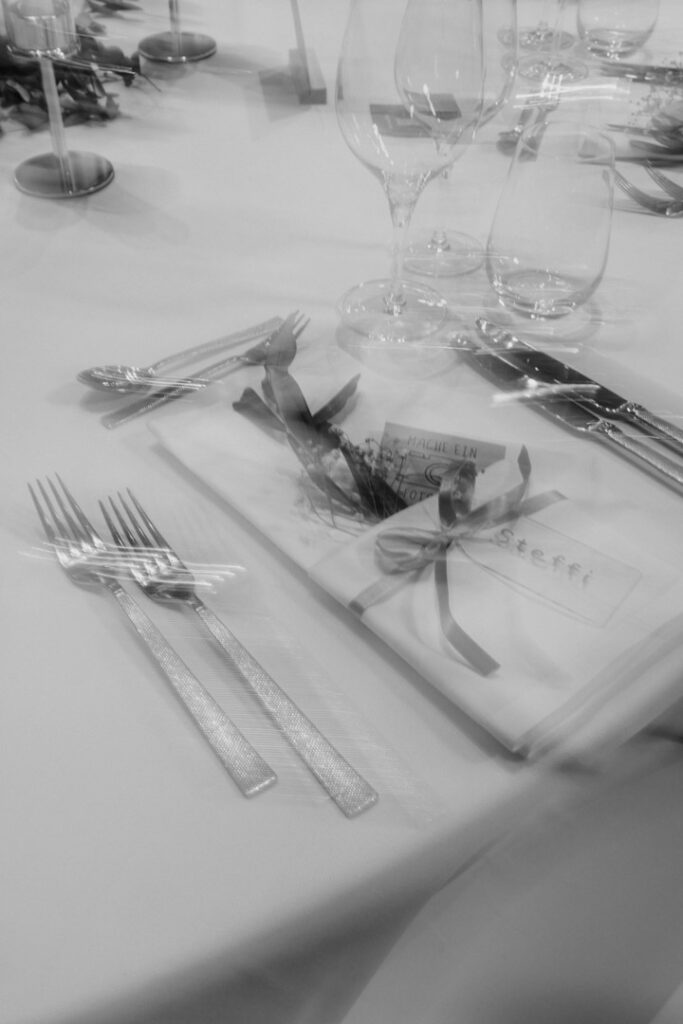 Nahaufnahme einer elegant gedeckten Tafel mit Besteck, Gläsern und dekorativem Namenskärtchen