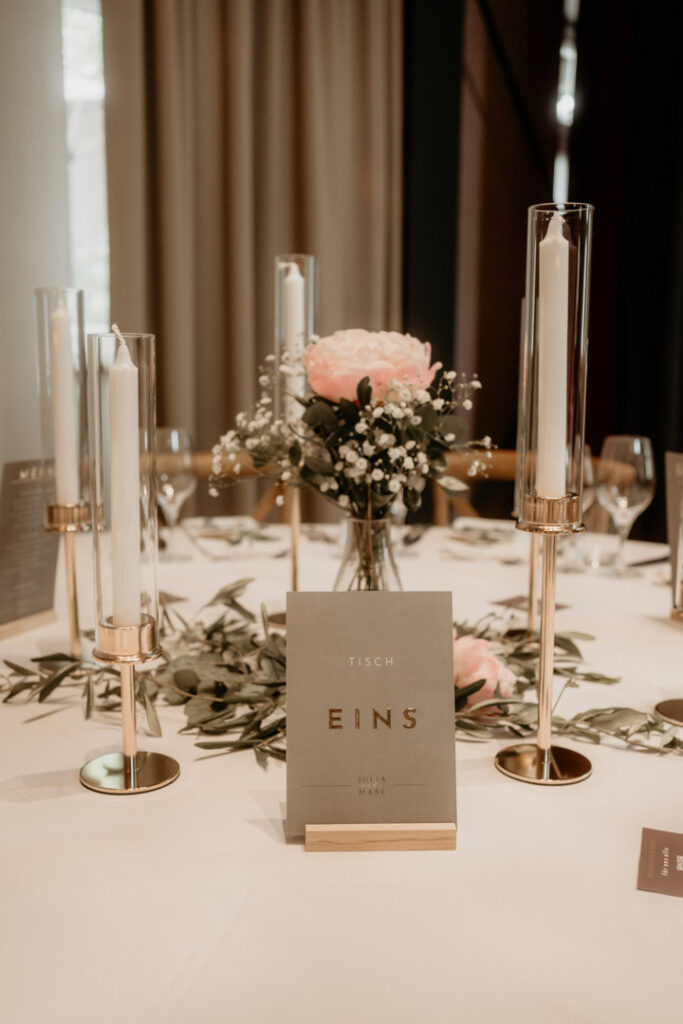 Stilvolle Tischdekoration mit Kerzen und Blumen bei der Hochzeit, festgehalten vom Hochzeitsfotograf.