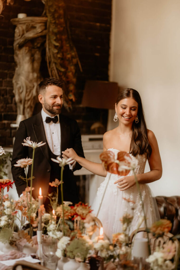 Brautpaar an einer elegant geschmückten Tafel mit Kerzen und Blumen in der Hochzeitslocation La Dü Düsseldorf, festgehalten in warmem Licht.